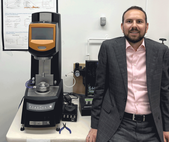 man in black suit standing next to lab equipment