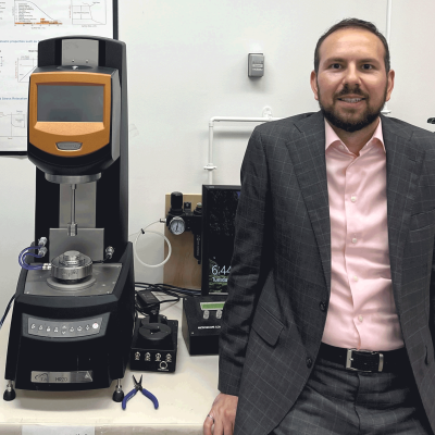 man in black suit standing next to lab equipment